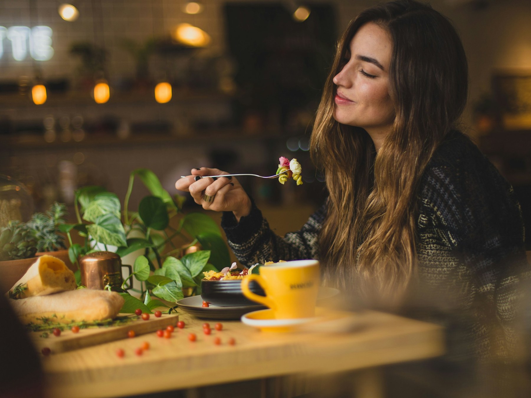 Woman dining alone at a restaurant table, enjoying a meal by herself