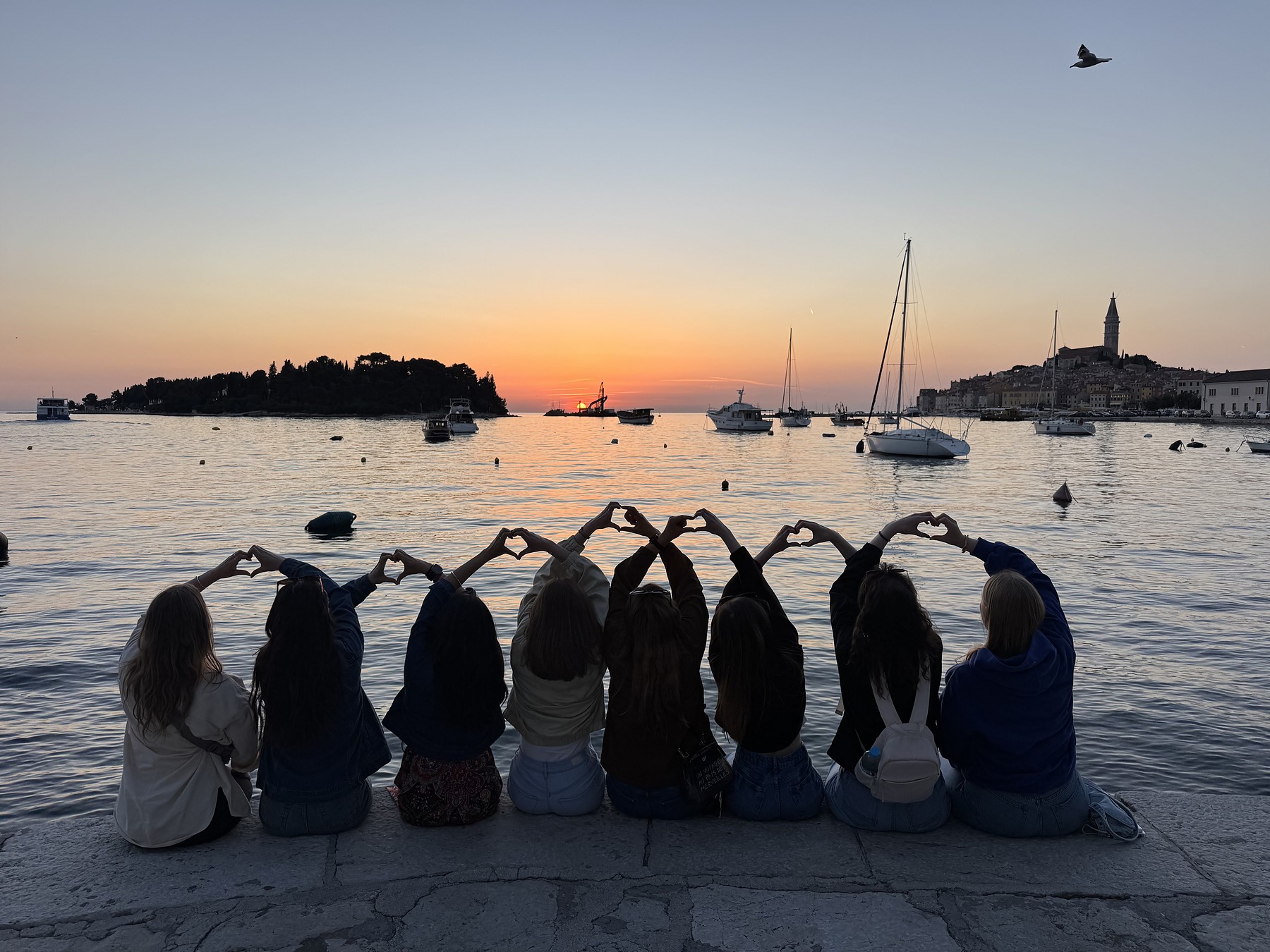 Solo women travellers forming hearts at sunset over Rovinj harbour, Croatia